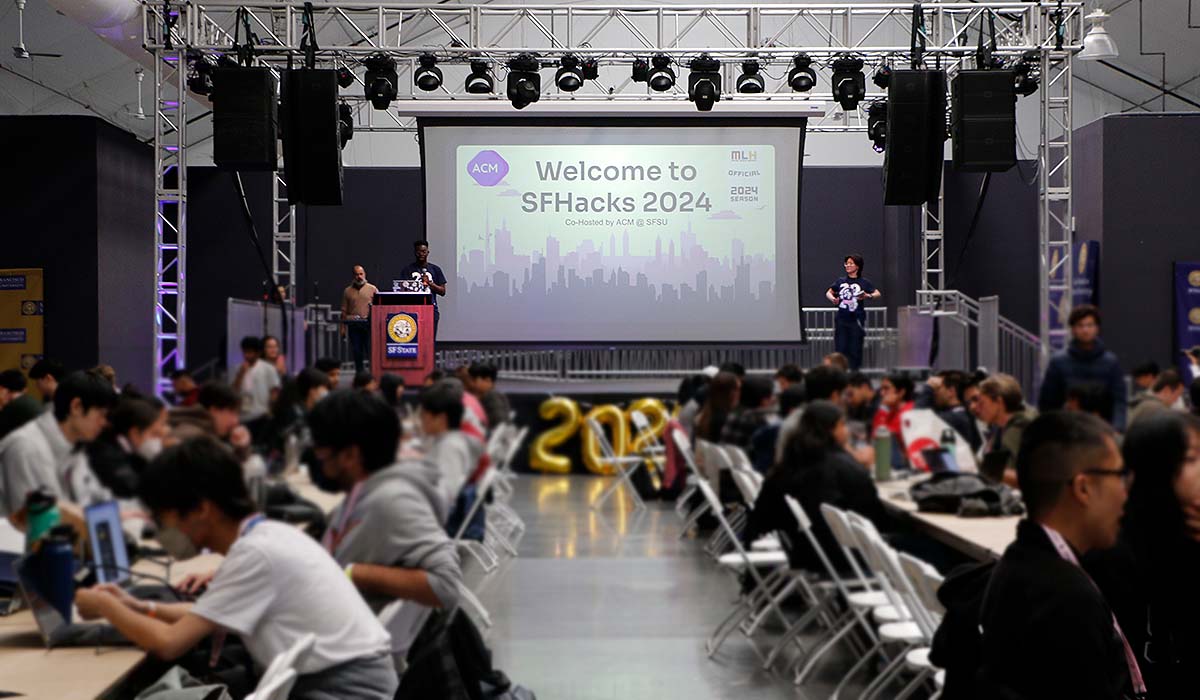 Event welcome slide on project and long tables filled with students