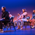 Actresses sit on chairs on stage