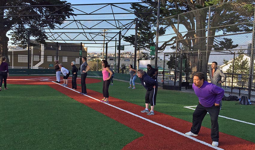 A group of people of varying ages work out at a park in San Francisco.