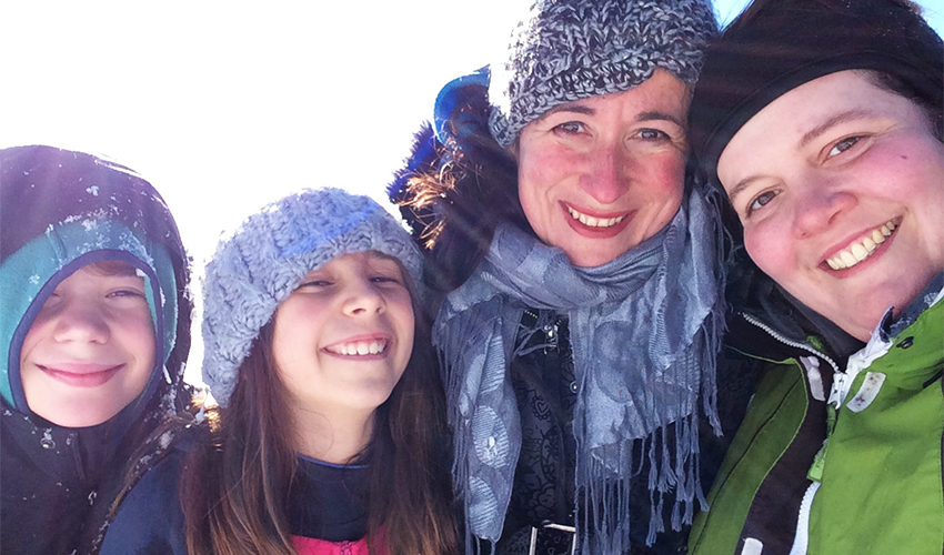 Assistant Professor Ana Luengo's son Niklas, daughter Milena, Ana Luengo and partner Lani Phillips, all smiling and bundled up in winter clothing.