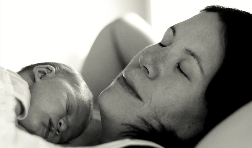 Mother cuddling with newborn baby.