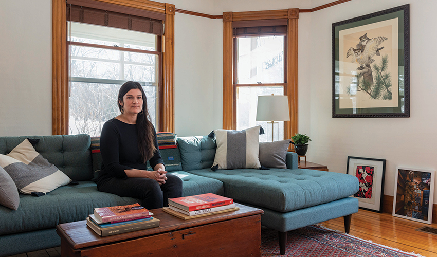 Photographer Brittany M. Powell sits on a couch inside her home