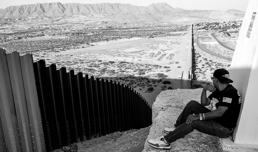 Deported U.S. Army veteran Jose Francisco Lopez Moreno overlooks the fence separating him from the United States.