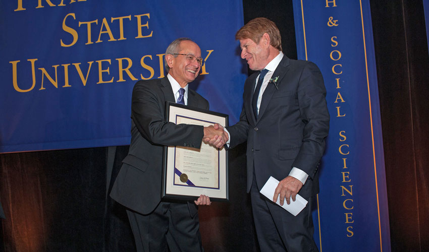 President Les Wong shaking hands with alum Gregory Fischbach as he presents Fischbach with a citation.