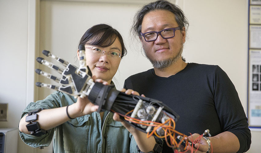 Associate Professor of Computer Science Kazunori Okada and Assistant Professor of Engineering Xiaorong Zhang in a lab with a prosthetic arm.