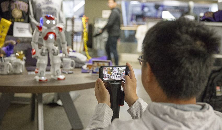 A student uses his iphone to films a Zorabot sitting on a display in the campus bookstore