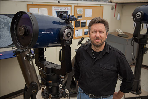 Professor Stephen Kane with a telescope in his SF State astronomy lab.