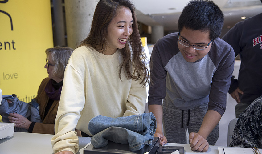 Two student volunteers weigh clothing donated by other students, faculty and staff at a Wear Movement takeback event on campus.