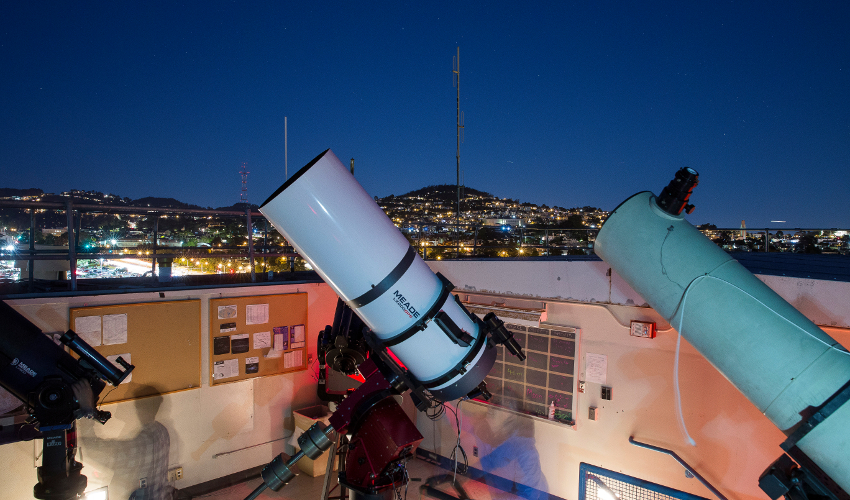 A time-lapse photo of students using three telescopes on the roof of the SF State Observatory