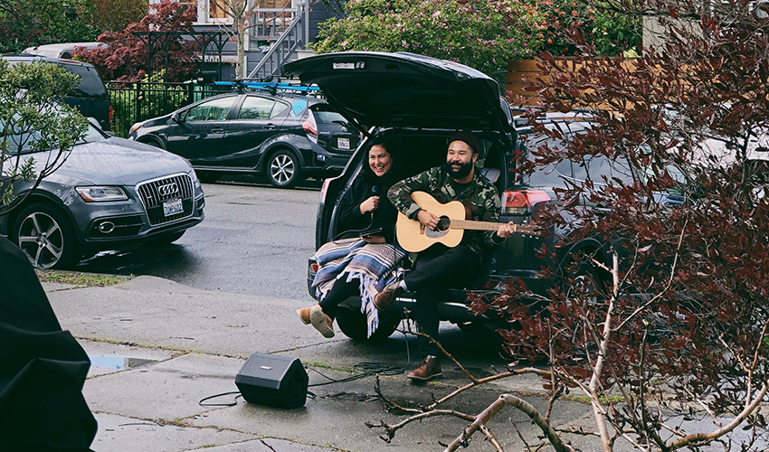Duo sits in the back of their station wagon and performs music