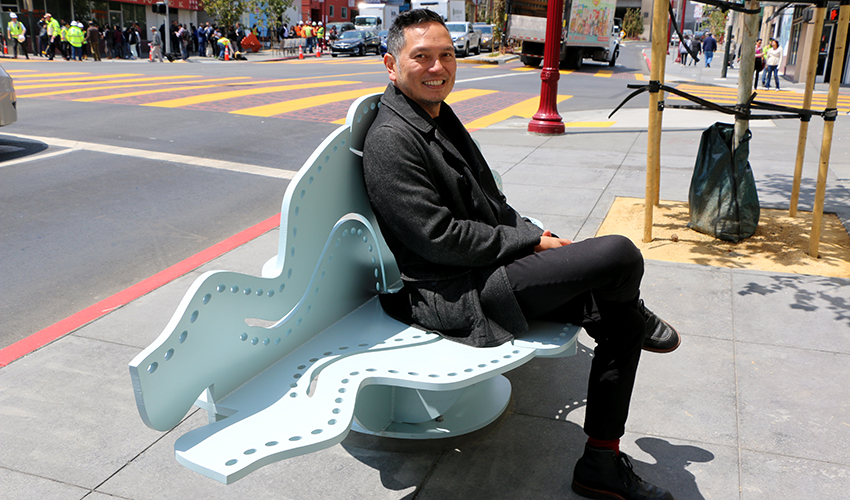 Artist Michael Arcega sits on a cloud-shaped bench that he created.