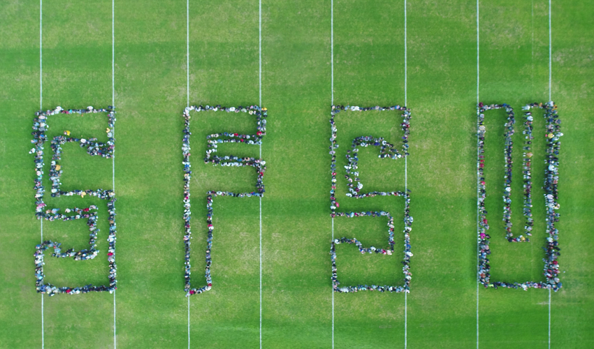 Students form the letters SFSU on a green field