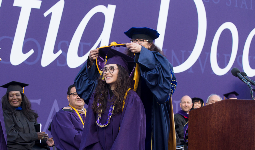 2019 hood recipient Chloe Zirbel receives the College of Science & Engineering hood from dean Carmen Domingo.