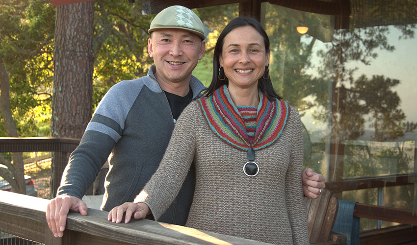 Man and woman smiling with trees in the background