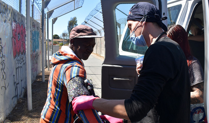 Person wearing gloves and a mask providing care to another person.