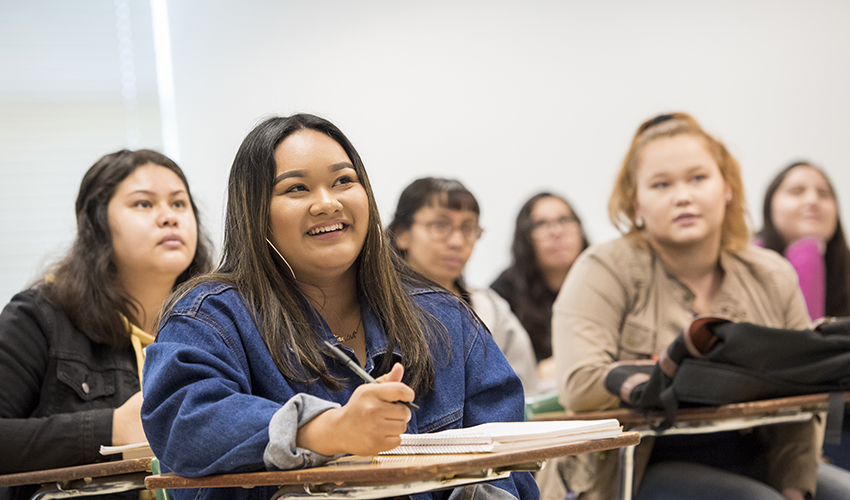 Group of students sitting in classroom chair desks looking in the same direction.