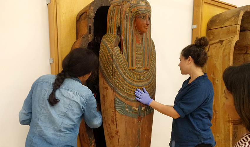 Photo of three people handling a sarcophagus