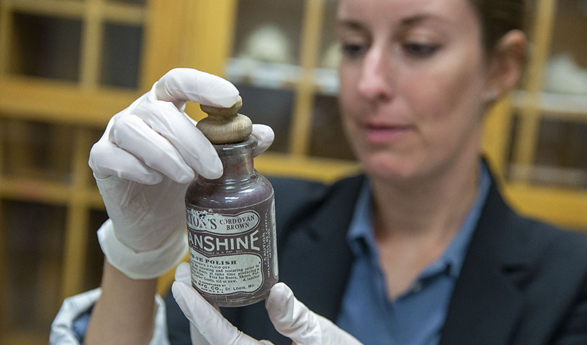 Professor examines an old bottle of shoe polish