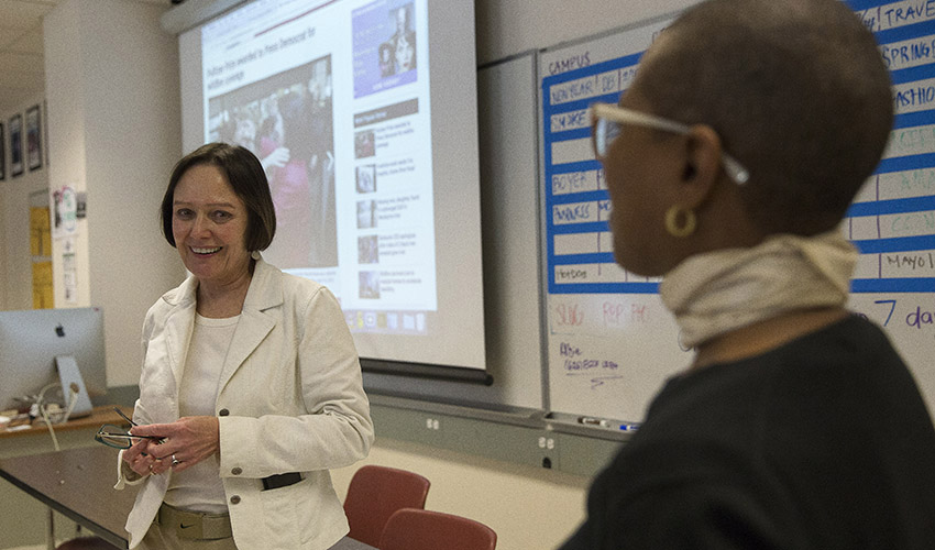 Joanne smiles and looks at Department Chair of Journalism Venise Wagner in a classroom