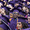 A photo of an SF State grad in a purple and gold gown amid other graduating students at Commencement 2015.