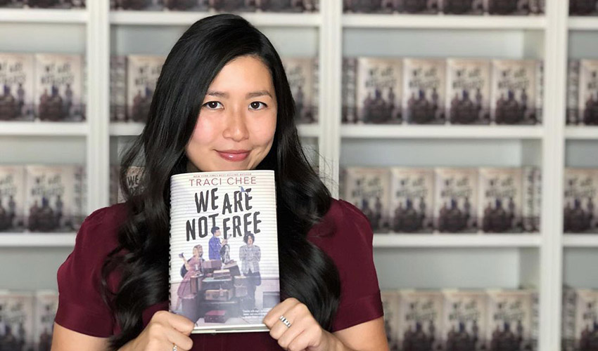 Author Traci Chee poses with her book"We Are Not Free"