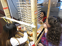 Three members of the SeismiGators team glue together pieces of balsa wood to create a five-foot tall, seismically sound structure for a national competition.