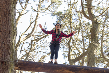 Student Kathy Vu balances on a utility pole at SF State's ropes course.