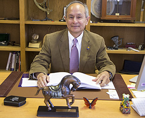 A photo of SF State President Leslie Wong at his desk with the APAHE President's Award.