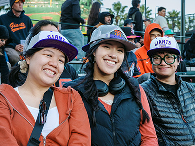 Three people smile while seated at Oracle Park