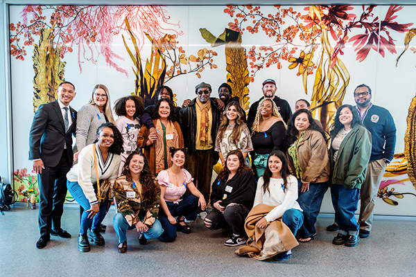 Guardian Scholars Program students pose for a group photo with Delroy Lindo in the hallway of the SFSU Science and Engineering Innovation Center