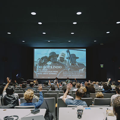 a movie theater with a screen and the backs of people's heads