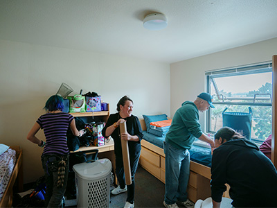 A family laughing while moving student into dorms