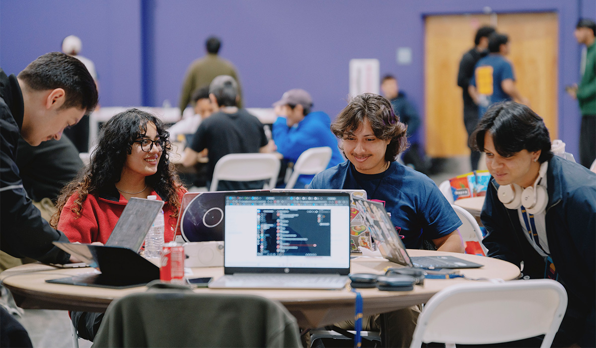 Four students chatting while working on their computers