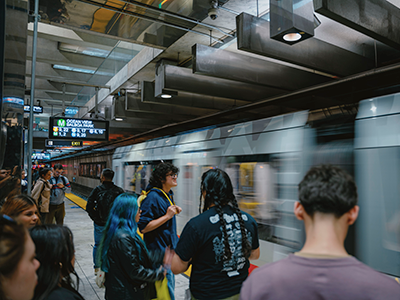 Students stand on the platform at the Muni Embarcadero station as a train passes by