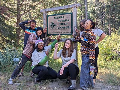 Six students standing around and pointing to Sierra Nevada Field Campus sign