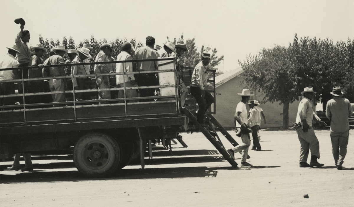 Agricultural workers exit the back of a truck in an archival photo