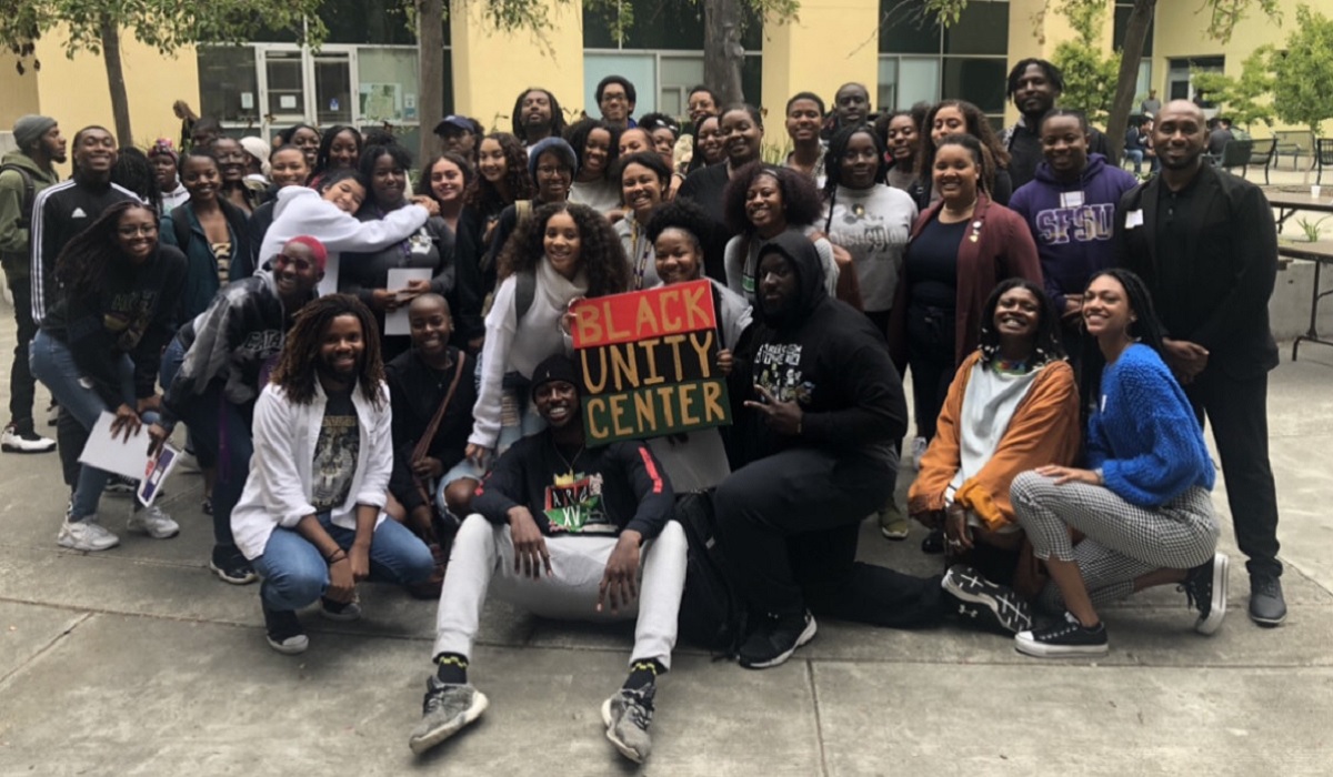 A group of students and staff members gather around a sign saying Black Unity Center