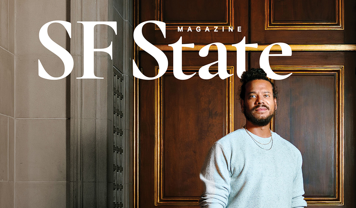 The SF State Magazine spring/summer 2026 issue cover photo of Ryan Marchand standing in front of a wooden door while wearing a gray sweatshirt and two necklaces