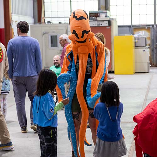 Person in squid costume dancing with two children