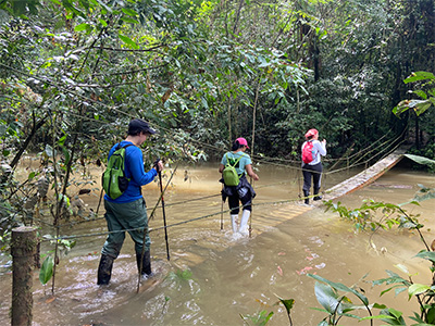Three students walking on a bridge submerged in water