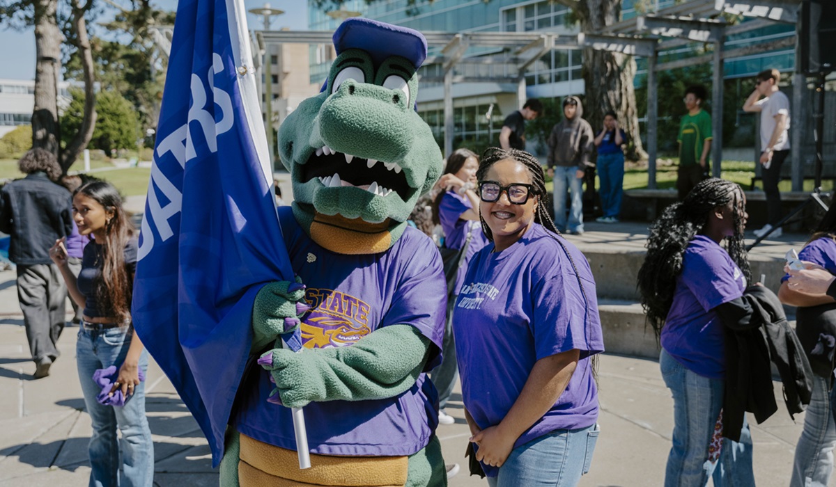 A person in a gator costume stands with a smiling person in a purple t-shirt