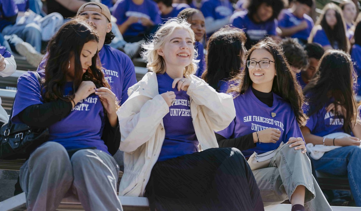 Students in SFSU T-shirts sit together on stadium bleachers