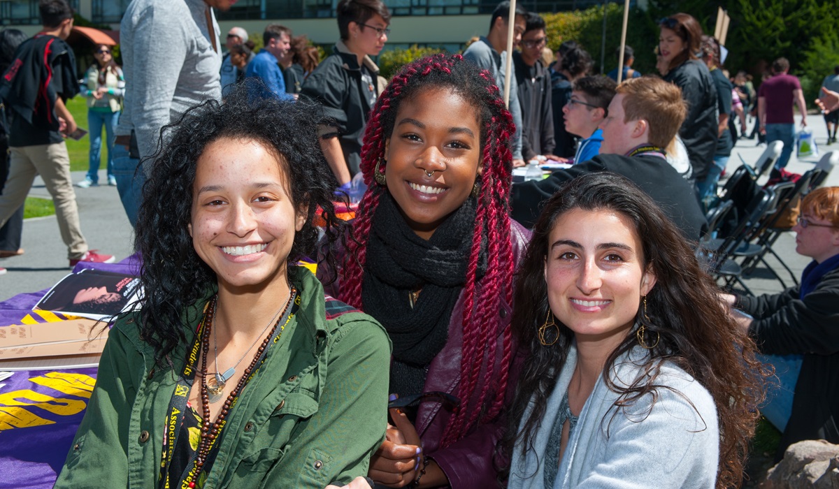 Three students smile at the camera