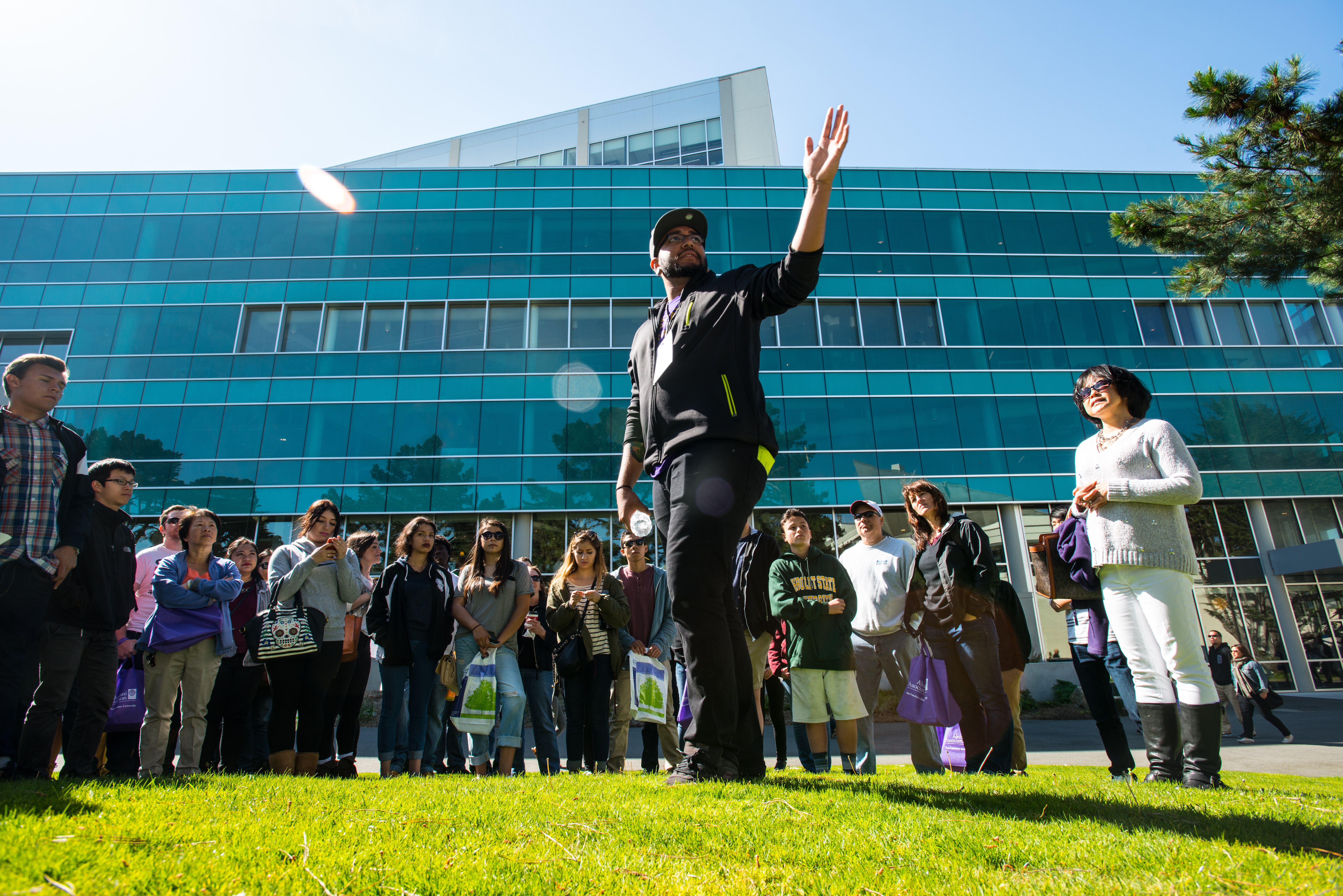 A man gestures to a tour group in front of the SFSU library