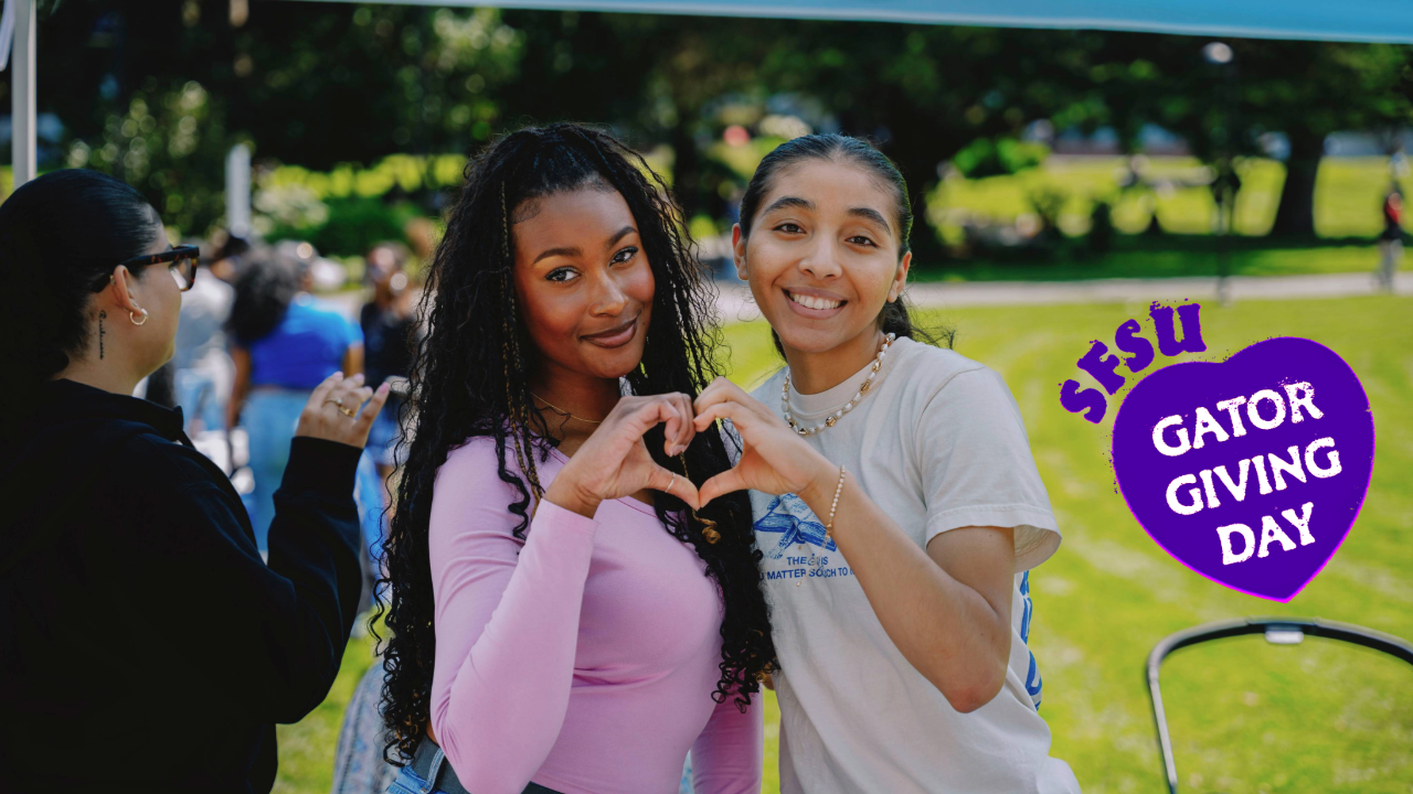 Two students make a heart shape with their hands with the Gator Giving Day logo pasted in the right side of the photo