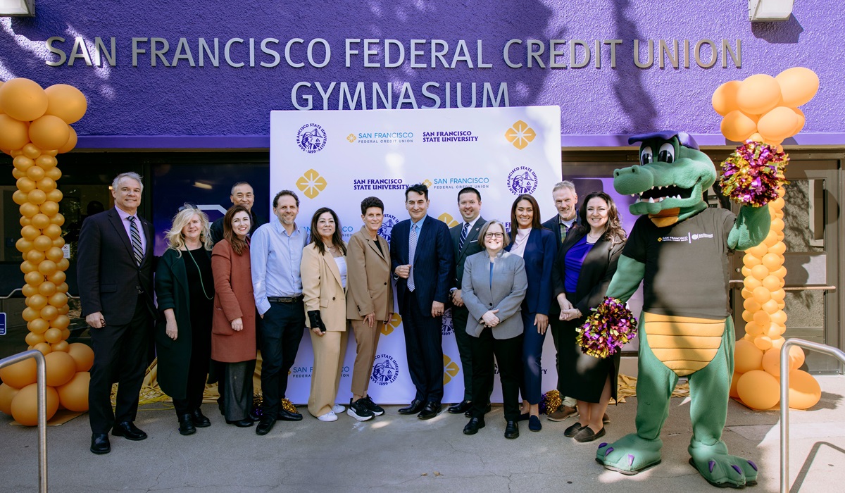 Alli Gator and a group of people in front of the new gym signage