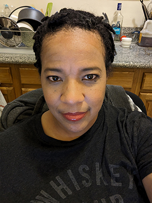 Jae Hamilton selfie while seated in front of a kitchen sink and window 