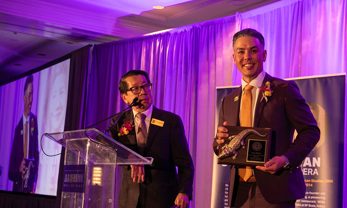 Two adults on the stage at the alumni hall of fame event,