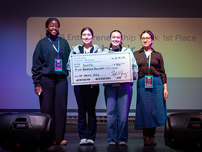 The four winners of the JFF Ventures Prize hold an oversized check while standing on a stage