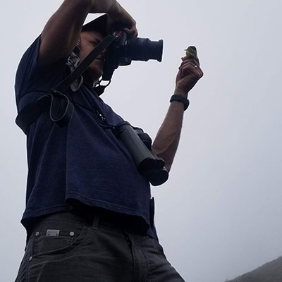 Jack Dumbacher taking a photo of a bird he's holding in his hand